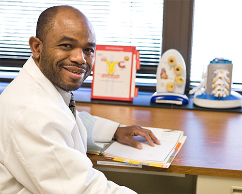 a man smiling at the camera with his hand on a binder