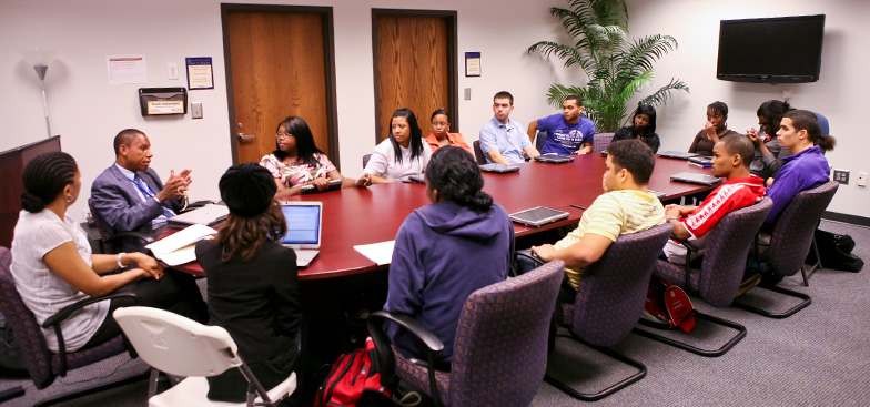 a group of students sit around an oval table